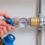 A hand turning a knob on a water pressure regulator.