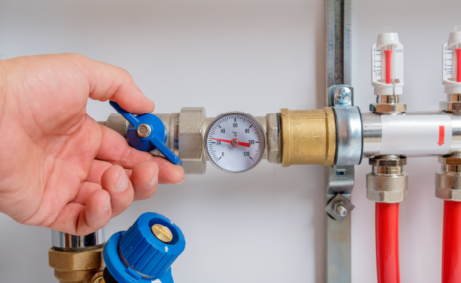 A hand turning a knob on a water pressure regulator.