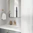Modern bathroom vanity with gold faucet, white countertops, and herringbone tile backsplash above the vanity.