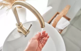 hand checking temperature of water flowing from high end faucet