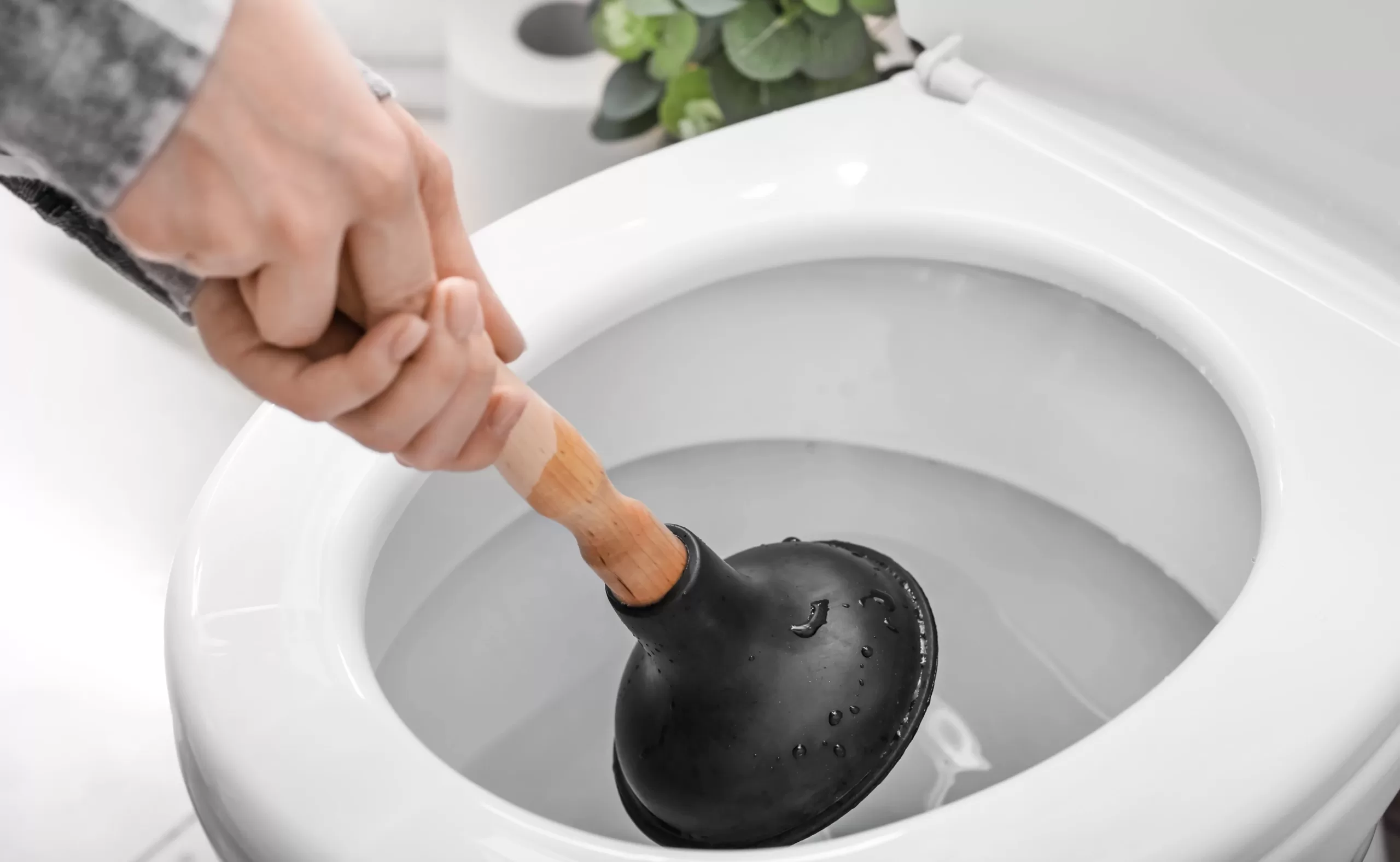Woman plunges her toilet after it overflows and waits for repair.