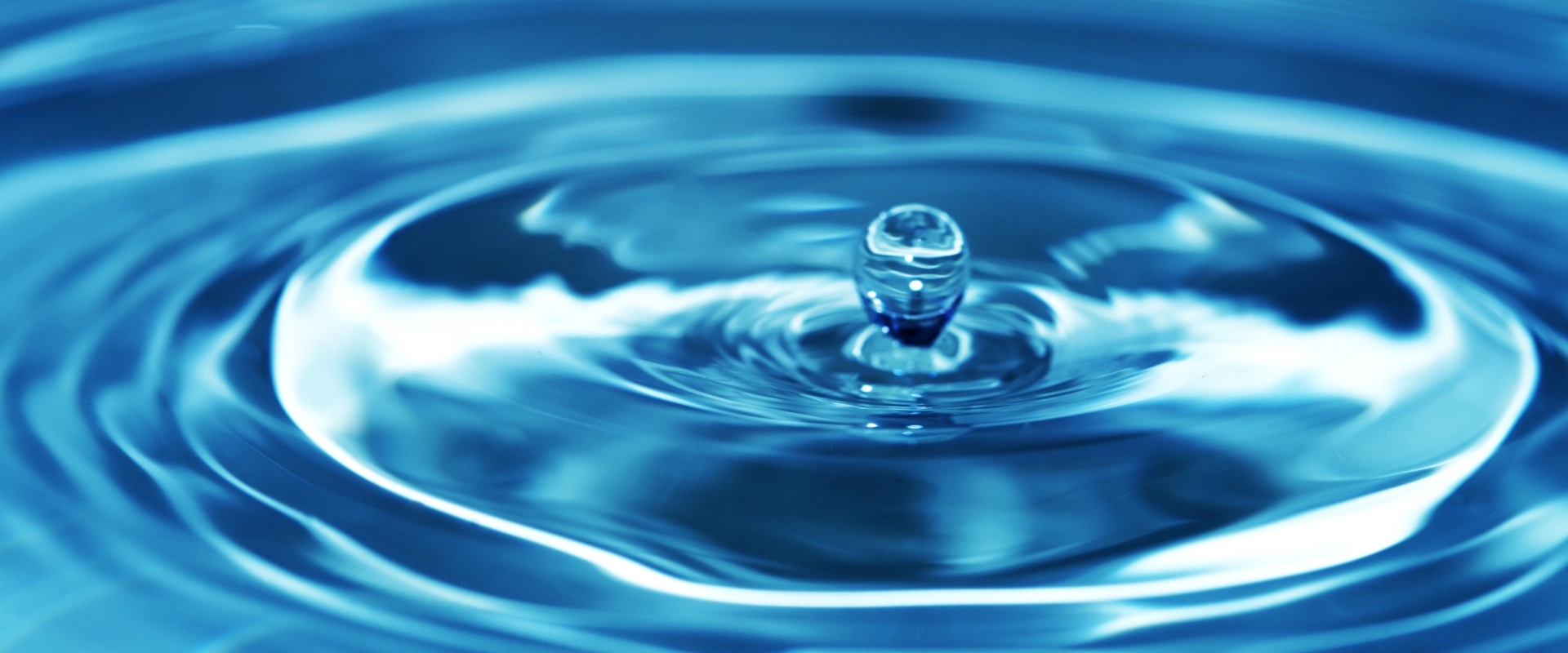 A drop of water falls into a larger body of water, causing a ripple effect.