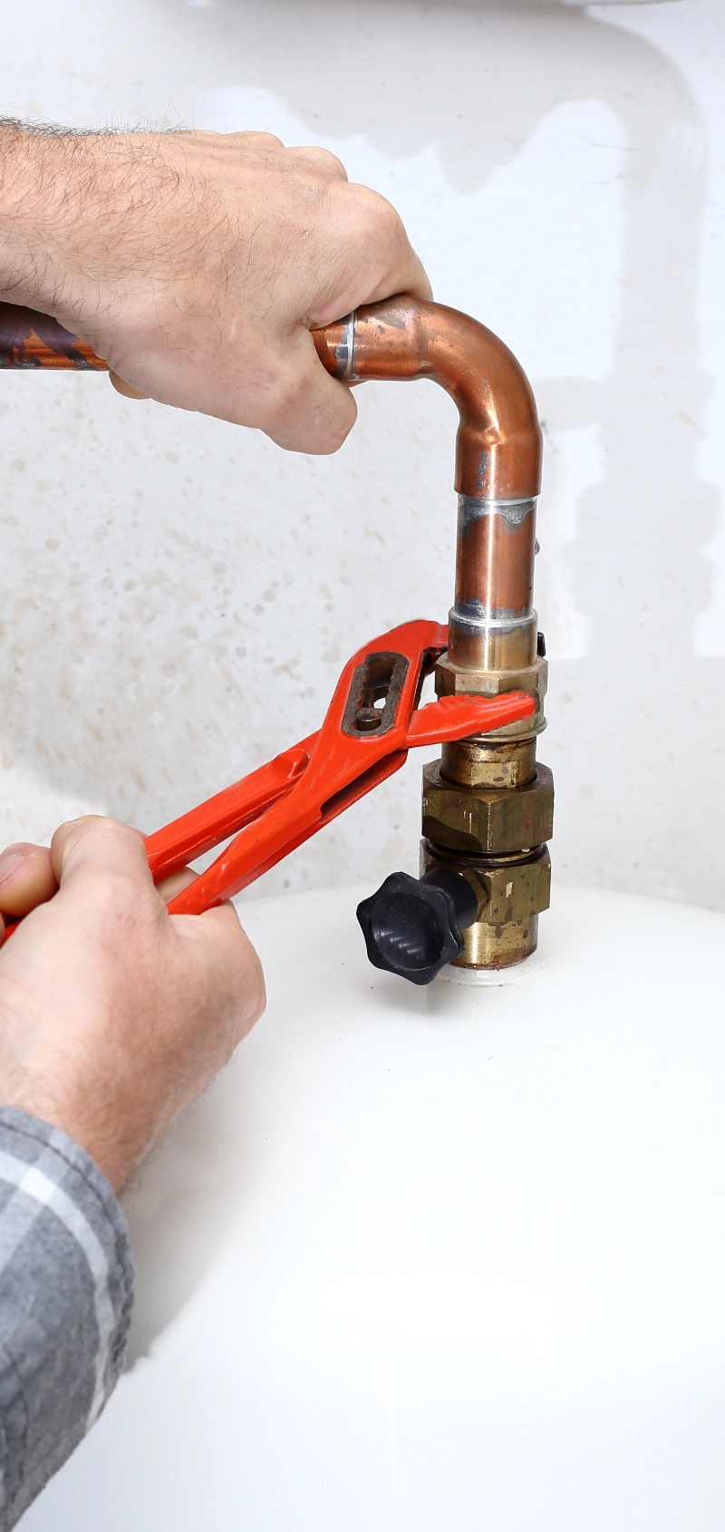 A plumber uses a wrench to tighten a pipe.