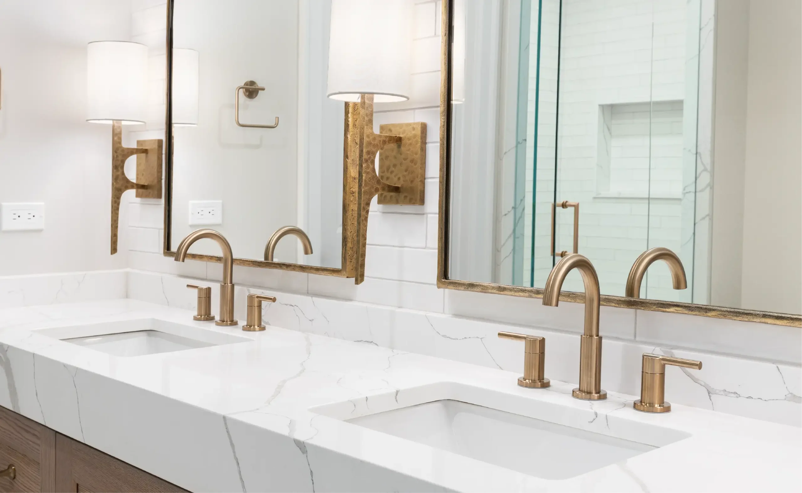 A modern bathroom, remodeled with a marble countertop and brass fixtures.