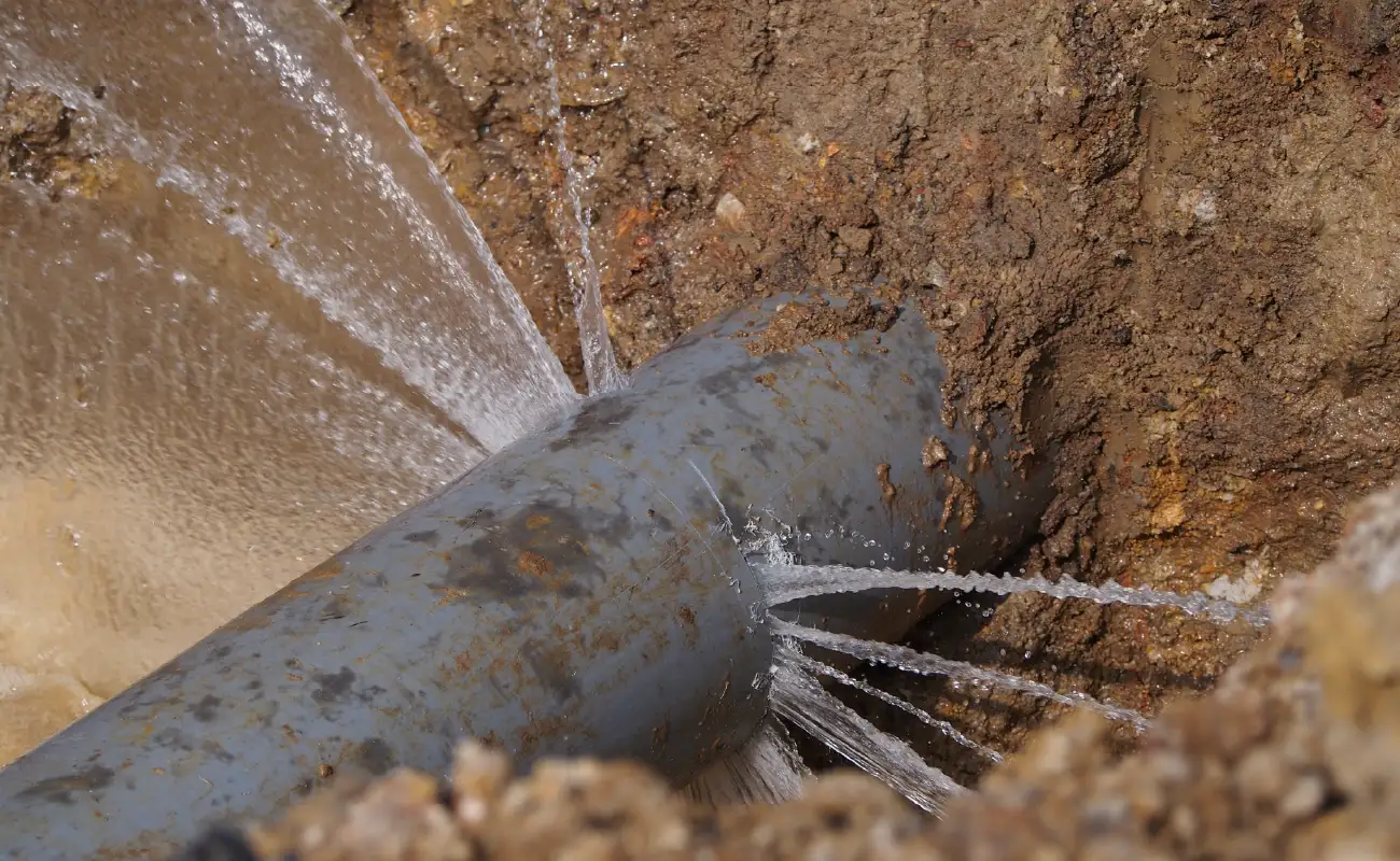Water bursting from pipe in the ground.