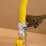 A silver wrench tightening a gas connector.
