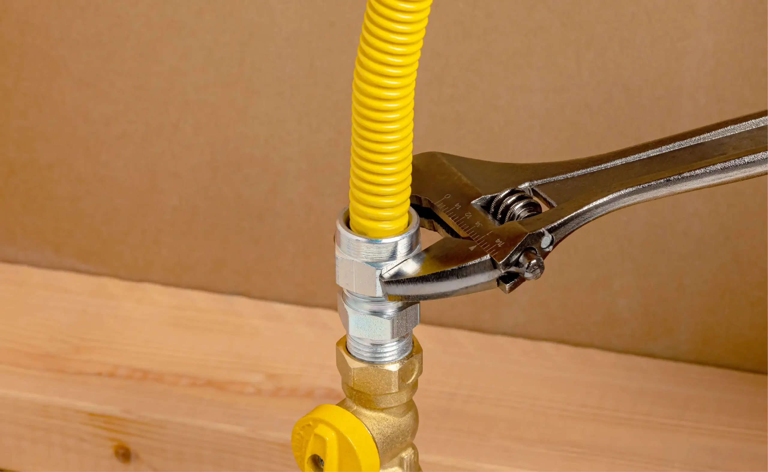 A silver wrench tightening a gas connector.
